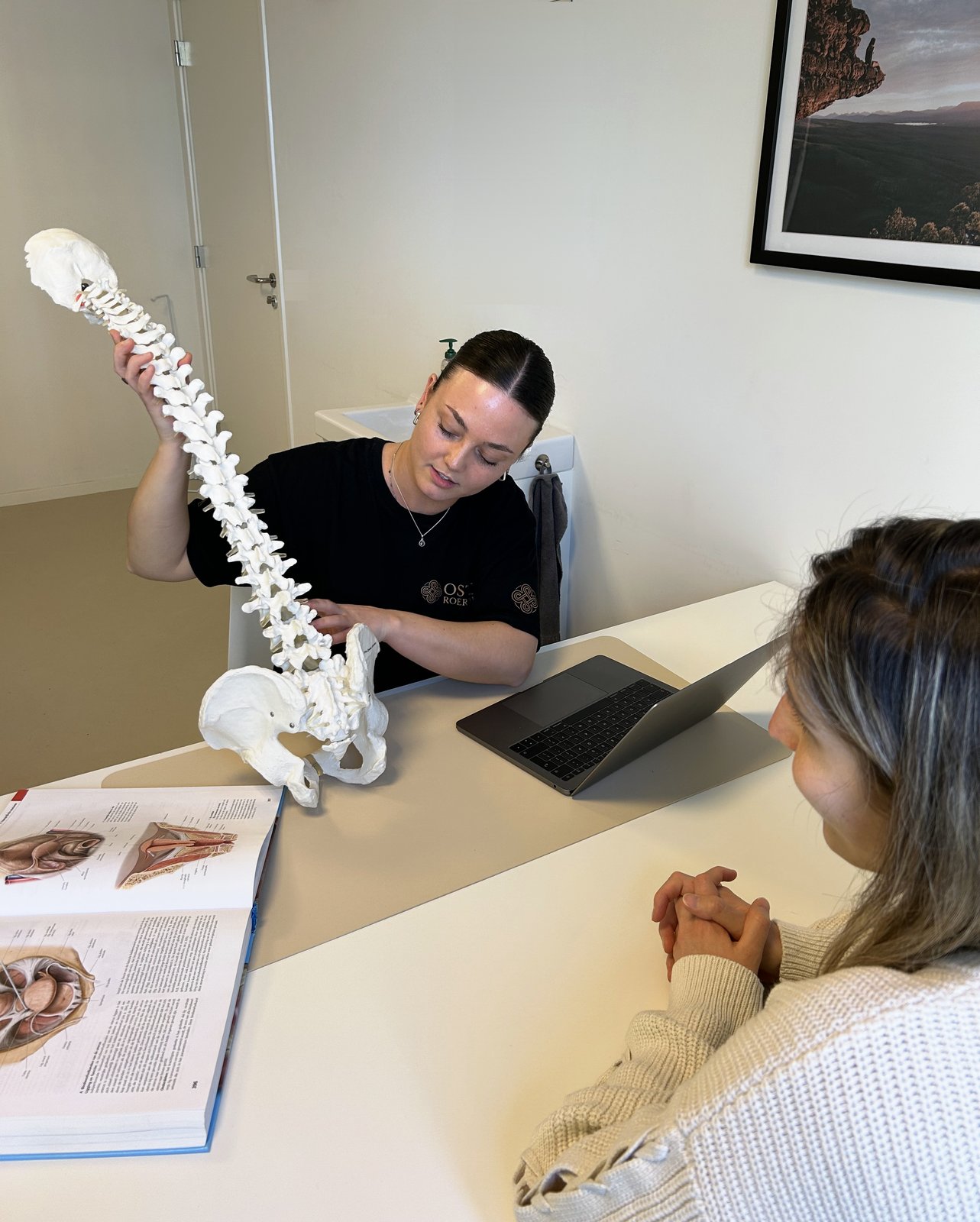 Osteopaat geeft uitleg over de wervelkolom aan een cliënt